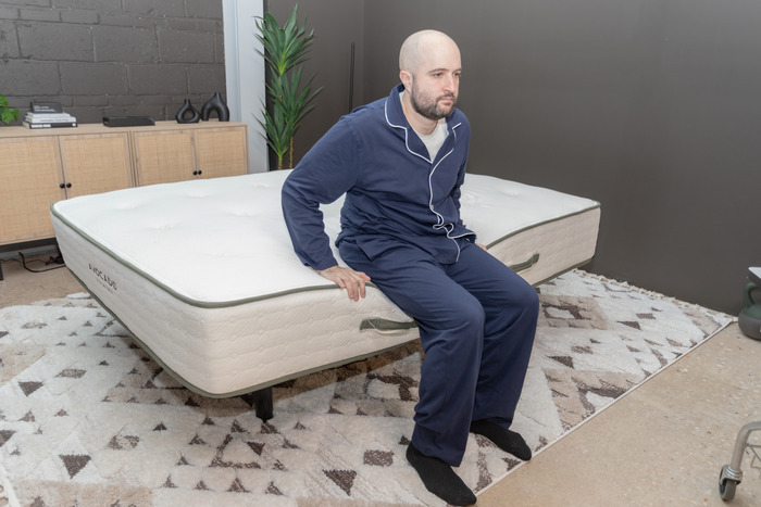 A man sitting on the edge of the Avocado Green mattress.