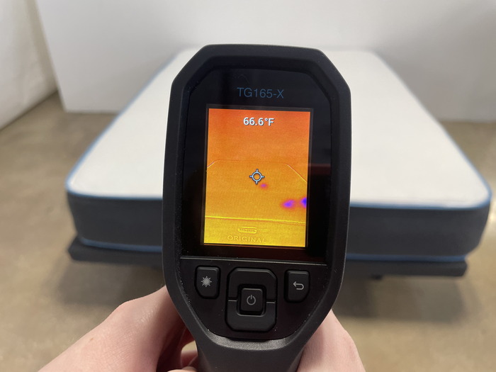 A closeup of someone pointing a thermal gun at the Bear Original mattress to read its temperature. The screen says 66.6 degrees.