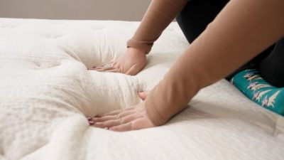 One of our mattress testers pressing into the cover of the Birch mattress to test its responsiveness.