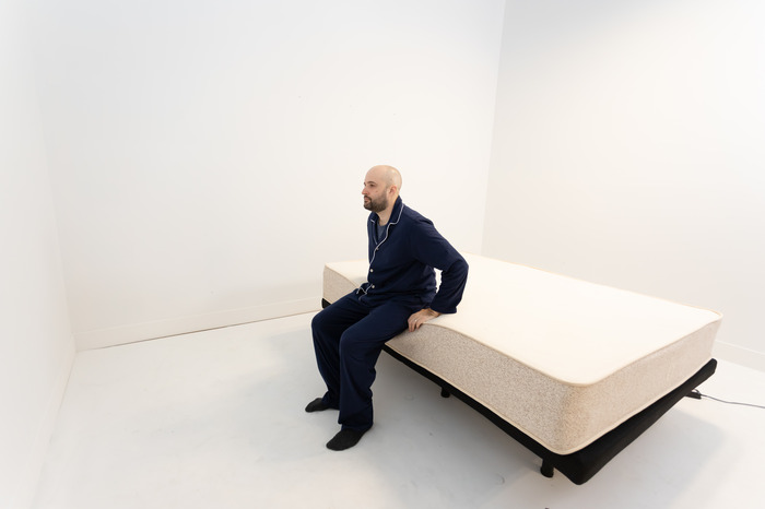 A man sitting on the edge of the Birch Natural mattress.