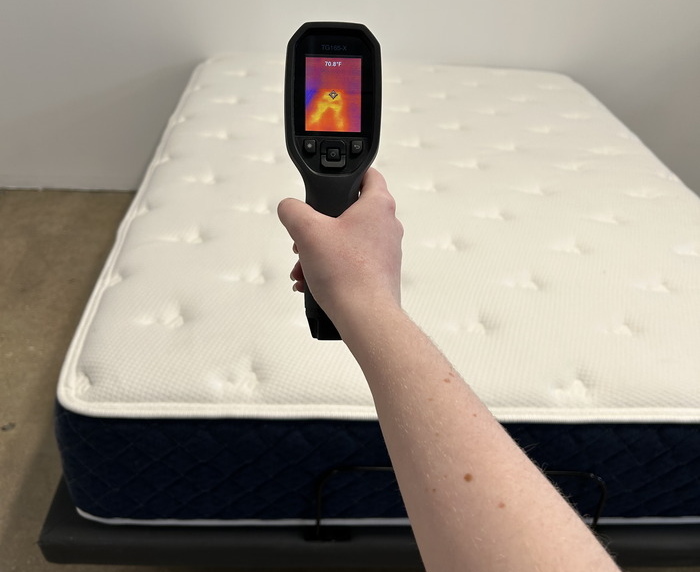 A closeup of someone aiming a thermal gun at the Brooklyn Bedding Signature Hybrid mattress in order to get its temperature.