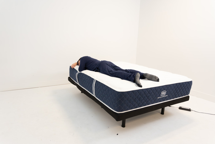 A man lying on the Brooklyn Bedding Signature Hybrid in the stomach-sleeping position.