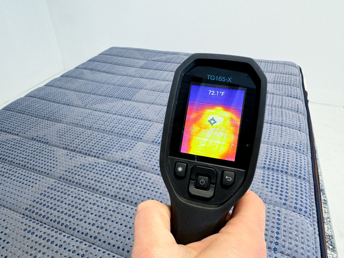 Someone aiming a thermal gun at the Brooklyn Bedding CopperFlex mattress to take its temperature.