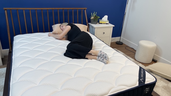 A woman sleeping on her side on the DreamCloud mattress.