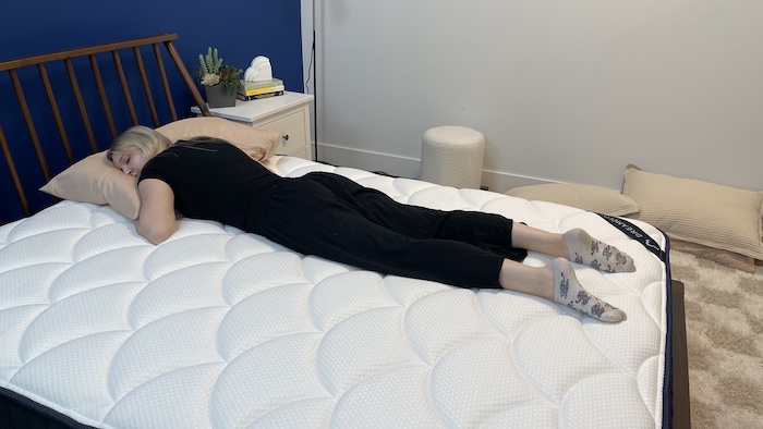 A woman sleeping on her stomach on the DreamCloud mattress.