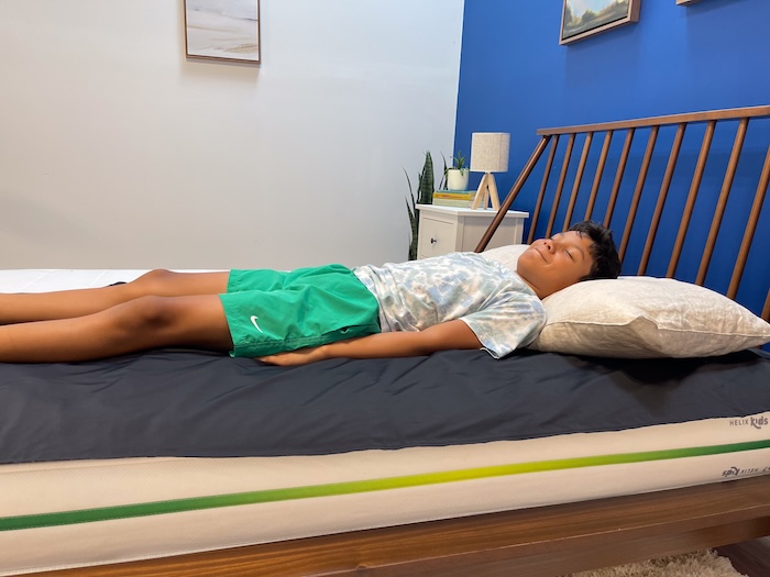 A 10-year-old boy sleeping on his back on the Helix Kids with his eyes closed.
