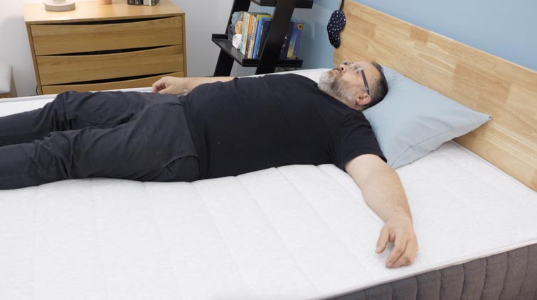 A man lying on his back on the Helix Plus mattress.