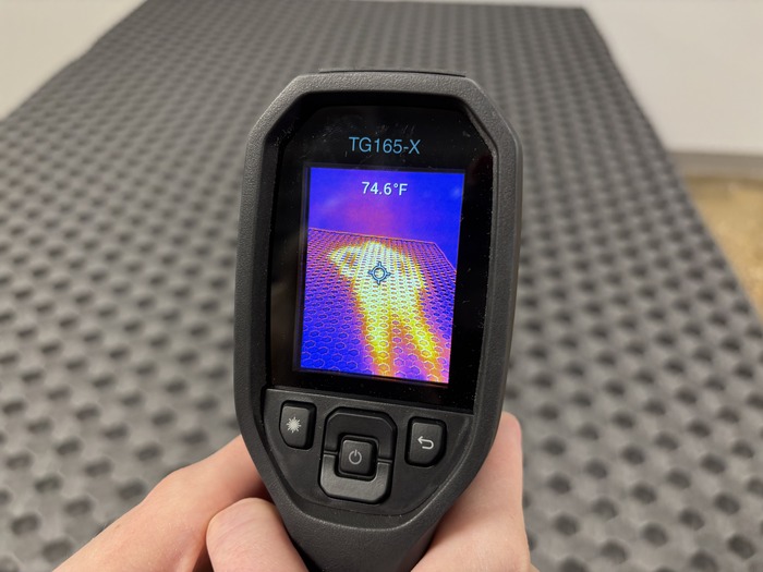A closeup of someone pointing a thermal gun at the firm side of the Layla to take its temperature after someone has rested on it for 5 minutes. The screen reads 74.6 degrees.
