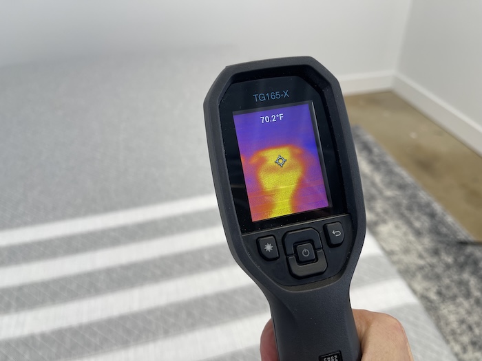 A closeup of someone using a thermal gun to read the temperature of the Leesa Original after 5 minutes of someone lying on the bed. The screen reads 70.2 degrees.