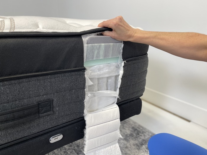 A closeup of the Nolah Evolution mattress's layers. A small section on the side of the bed has been cut out, showing the layers of foam and springs.