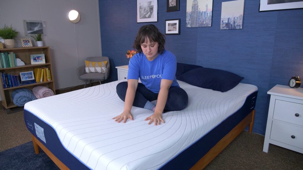 A woman sitting crosslegged on the Octave Vista mattress and pressing into its cover.