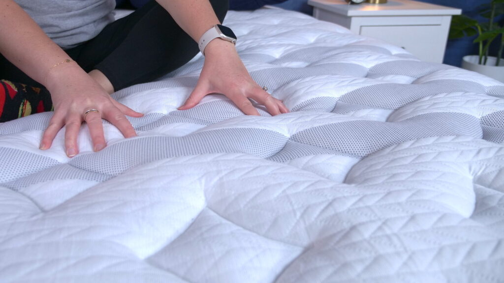 A woman sitting on the Leesa Sapira Chill mattress and pressing into its cover.