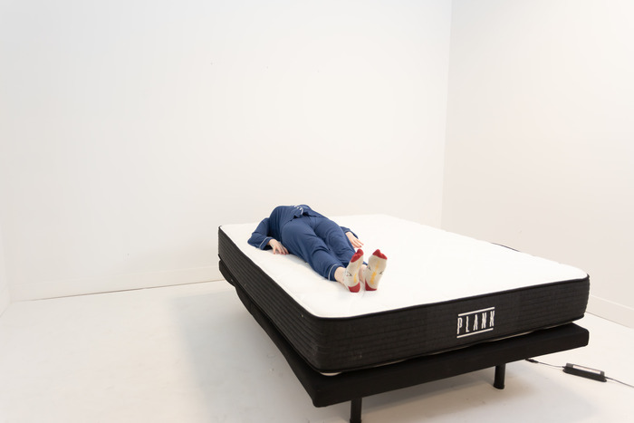 A woman lying on her back on the Plank Firm mattress.