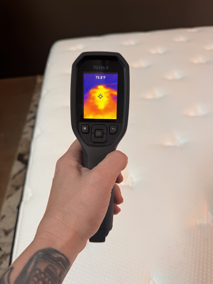 A closeup of someone aiming a thermal gun at the Plank Firm to read its surface temperature after someone has rested on it for 5 minutes. The temperature reads 75.8 degrees.