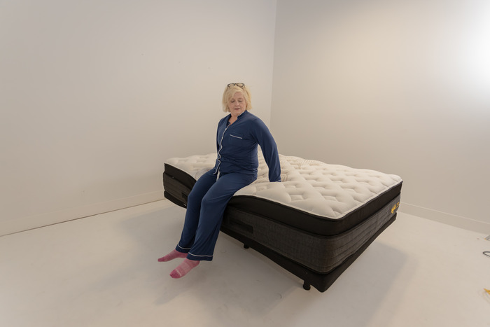 A woman sitting on the edge of the Nolah Evolution mattress to test its edge support.