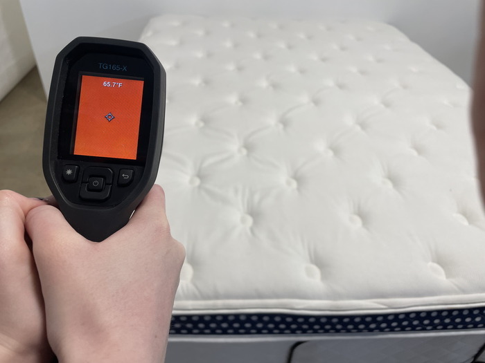 A closeup of someone using a thermal gun to measure the WinkBed's neutral temperature. The screen reads 65.7 degrees.