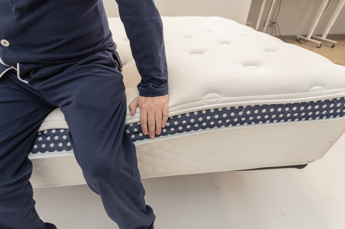 A man sitting on the edge of the WinkBed Plus mattress to test out its edge support.